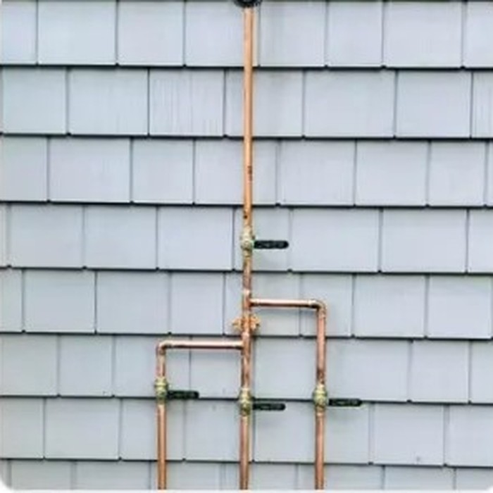 New copper water lines run on a shingled exterior wall